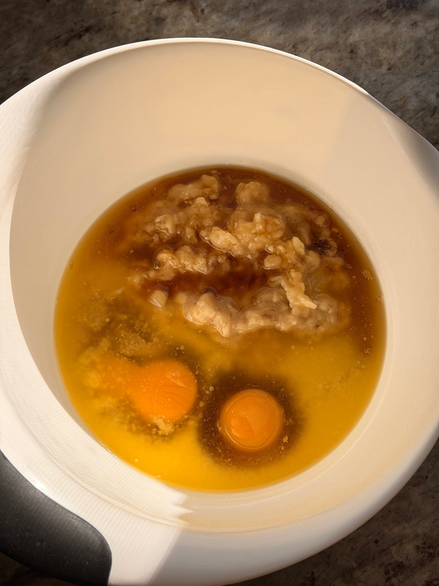 White bowl with brown liquid, egg yolks, and pieces of meat on a dark surface – photo 4